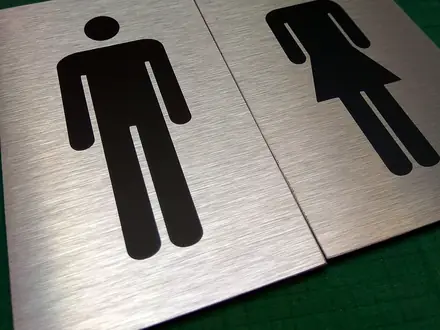 Piktogramy WC muž a žena na brúsenej hliníkovej tabuľke