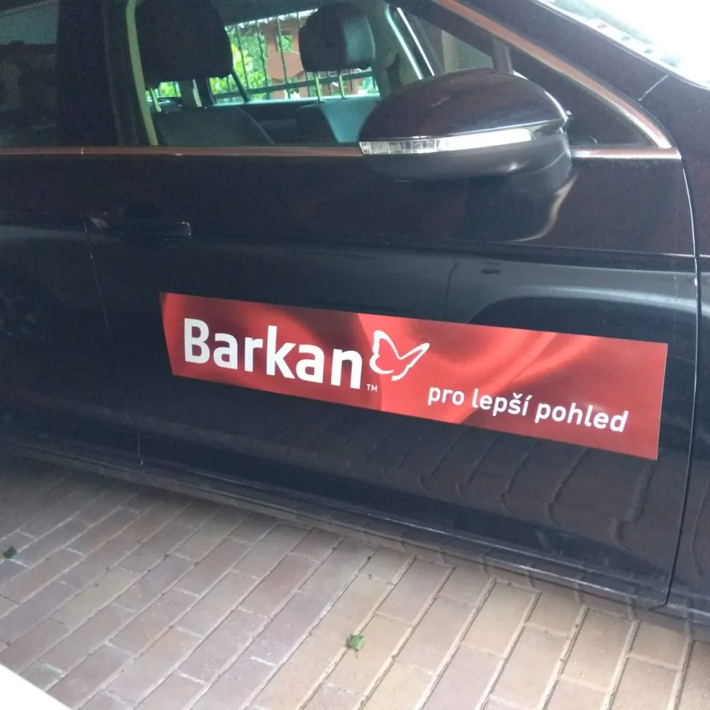 Červená obdĺžniková reklamná magnetka s logom na dverách čierneho auta
