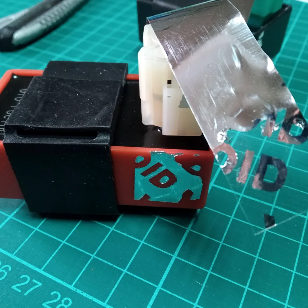 Odlepená strieborná VOID nálepka na elektronickom module, na jeho povrchu zostal nápis VOID